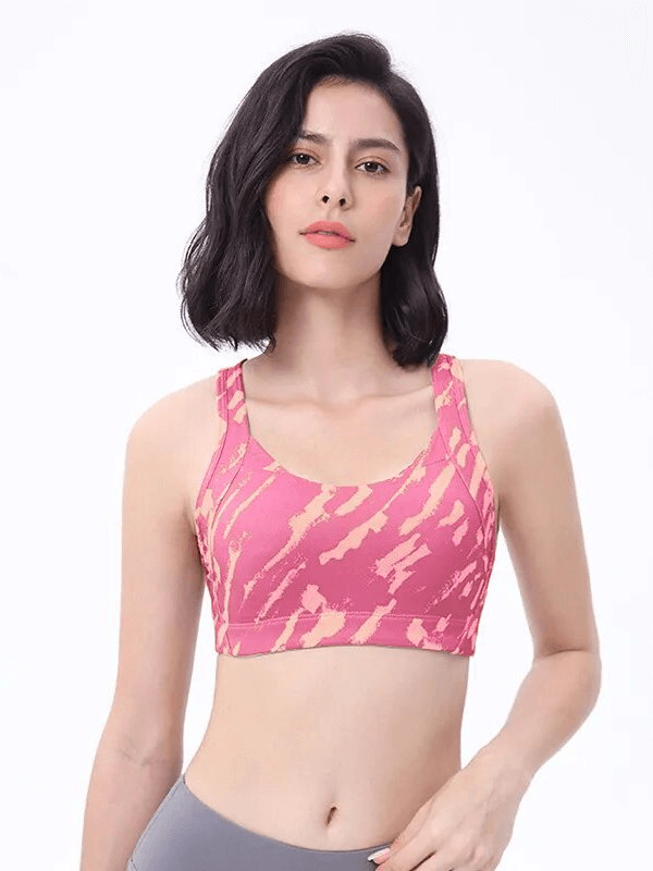 Woman wearing a stylish pink elastic sports bra with cross back, ideal for workouts. Breathable and lightweight fabric, product code SF1610.