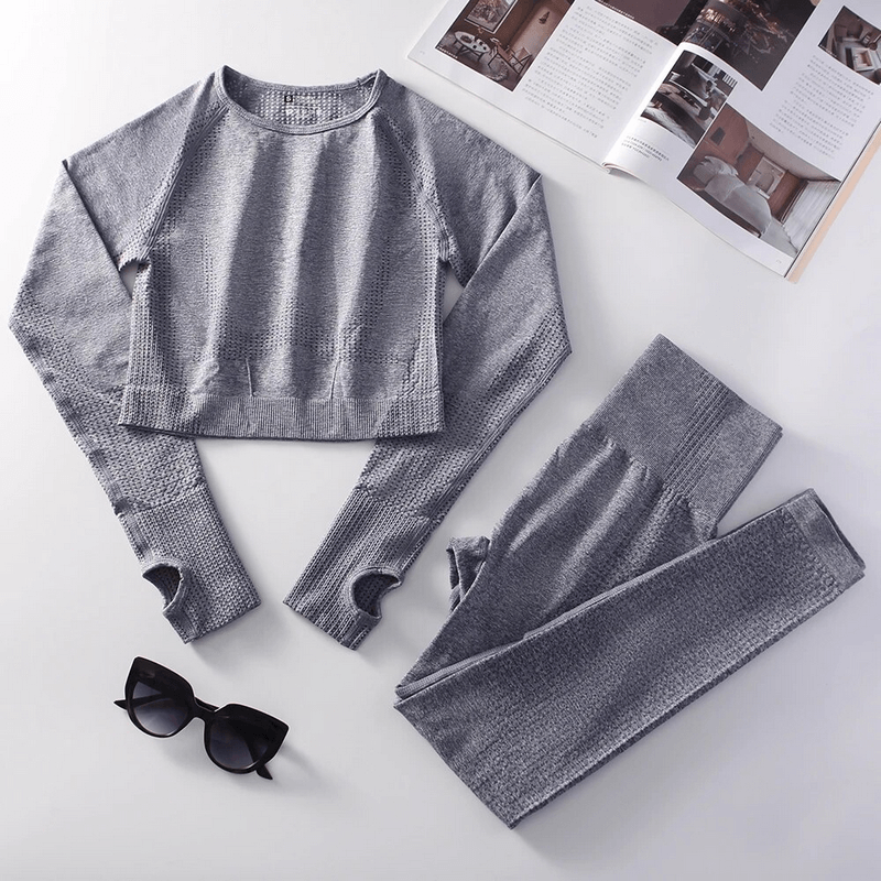 Stylish gray elastic women's suit with textured top and leggings, ideal for yoga or workouts, paired with chic sunglasses.