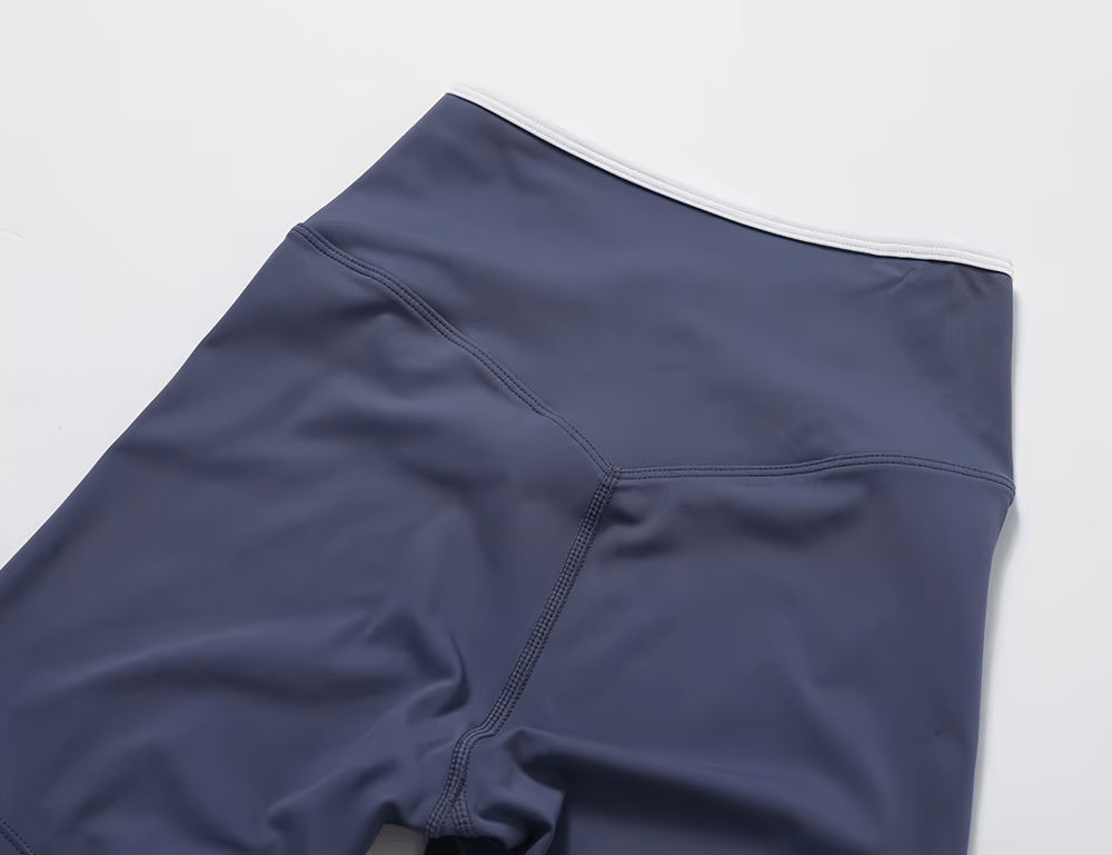 Close-up of navy high-waist flared yoga pants showing elastic waist and sleek stitching detail. Perfect for activewear elegance.