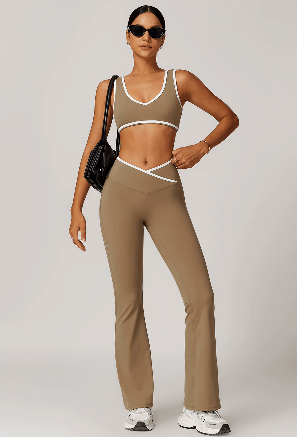 Woman wearing stylish high-waist flared yoga pants with a matching top, accessorized with sunglasses and a handbag.