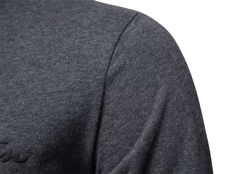 Close-up of stylish men's cotton long sleeve top with subtle letter print, showcasing breathable fabric texture and solid design.
