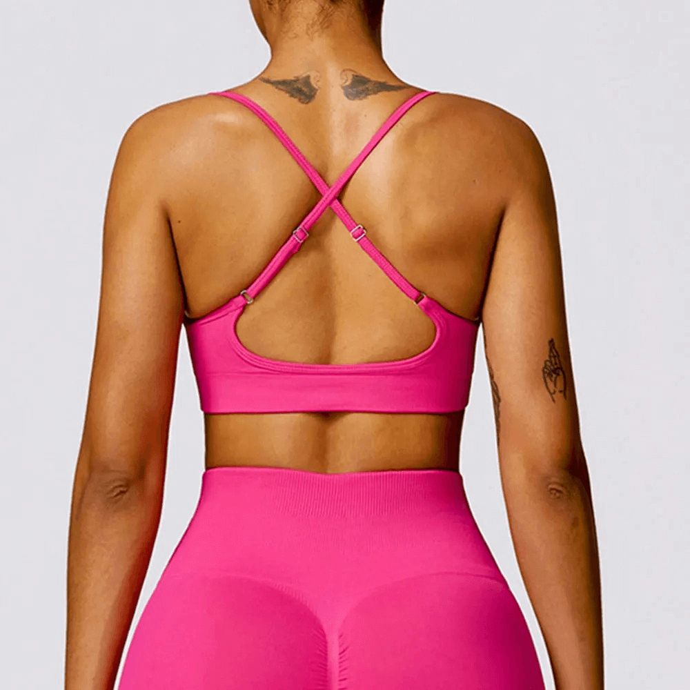 Woman wearing pink seamless yoga bra with criss-cross straps, SF2452, perfect for fitness and running sessions.