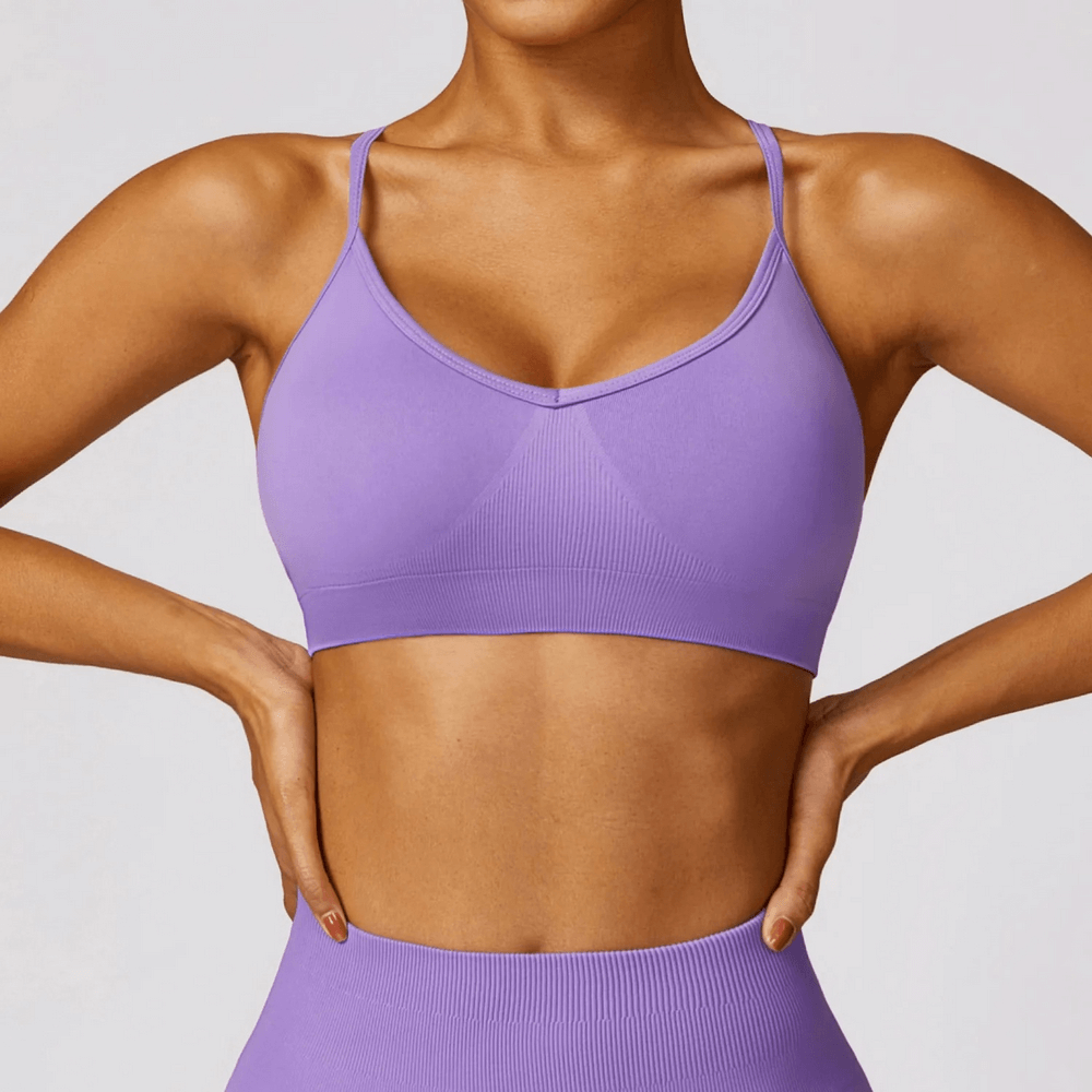 Stylish seamless purple yoga bra with criss-cross straps, high support for fitness, made from breathable nylon and spandex.