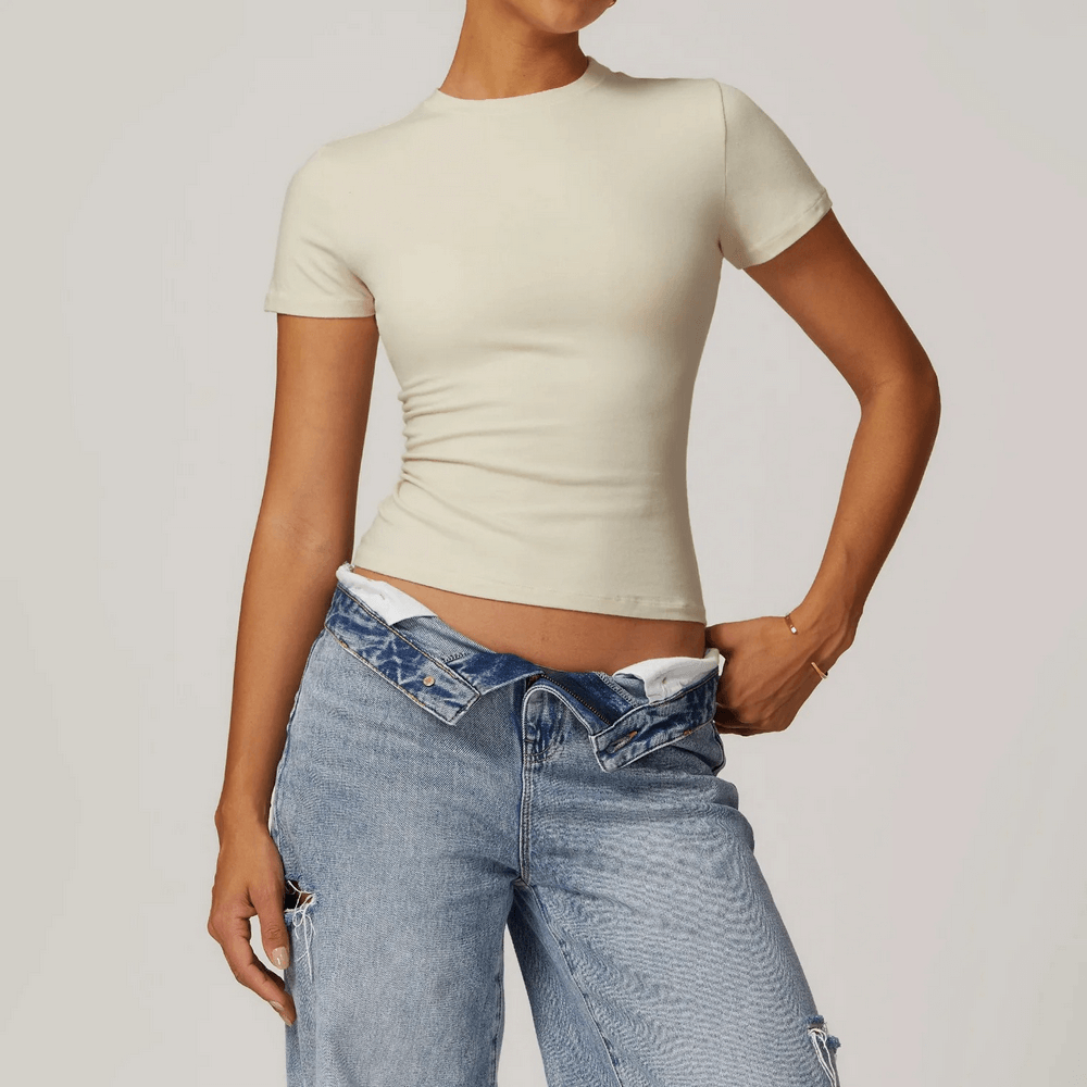 Woman wearing a stylish short-sleeve beige yoga t-shirt paired with ripped jeans.