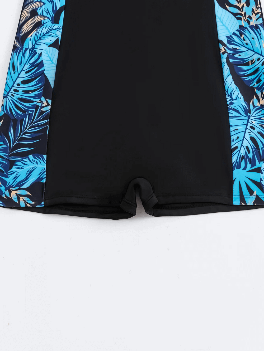 Close-up of stylish tropical print zip-up women's surfing swimsuit showing blue leaf side panels, enhancing movement and flexibility.