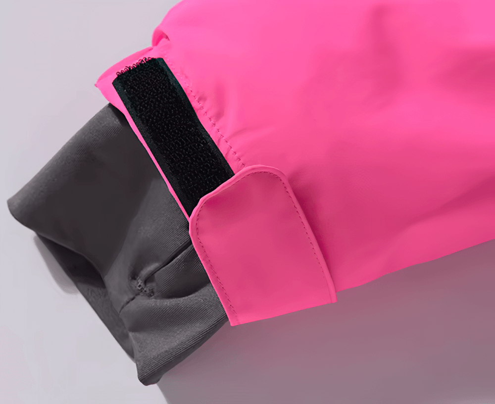 Close-up of a vibrant pink waterproof ski jacket sleeve with adjustable strap for skiing and snowboarding.