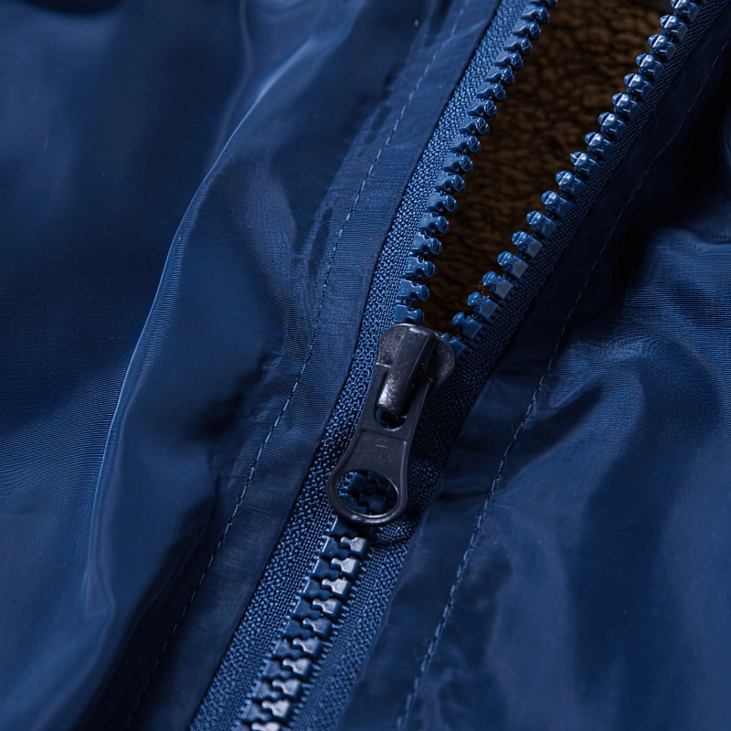 Close-up of a blue zipper on a stylish windproof women's windbreaker with floral print, featuring a hood and durable polyester material.