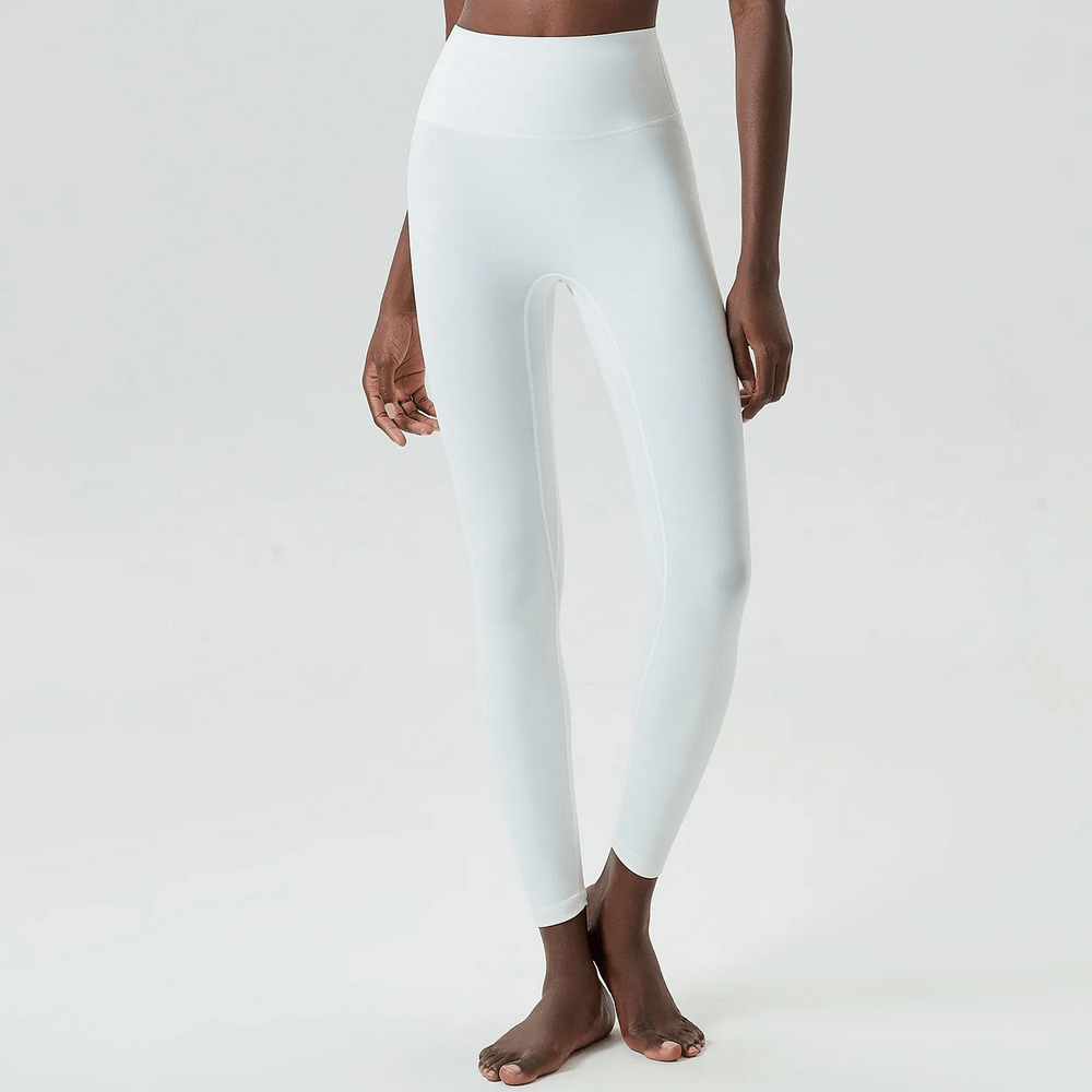 Woman wearing stylish white ankle-length yoga leggings for versatile workouts, featuring a snug elastic waist and durable knitted fabric.