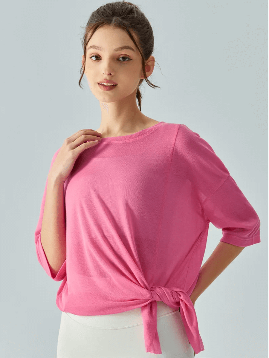 Woman in vibrant pink loose-fit short-sleeved t-shirt with side tie, showing relaxed and trendy style for casual outfits.