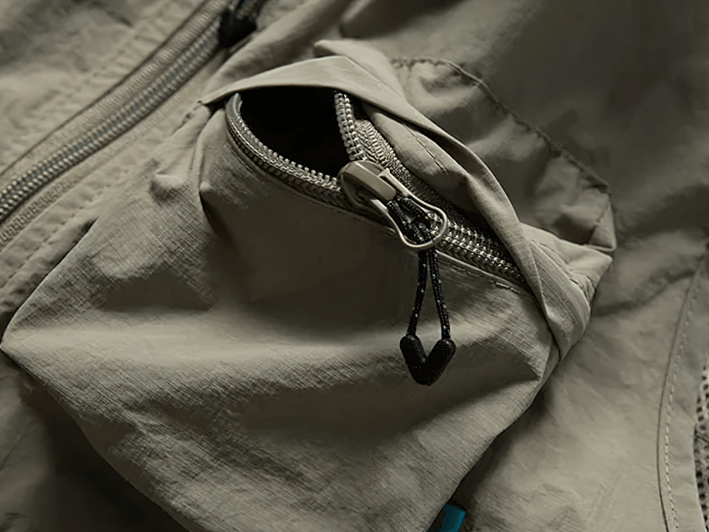 Close-up of tactical utility vest with zippered pocket, showcasing durable stitching and functional design for outdoor adventures.