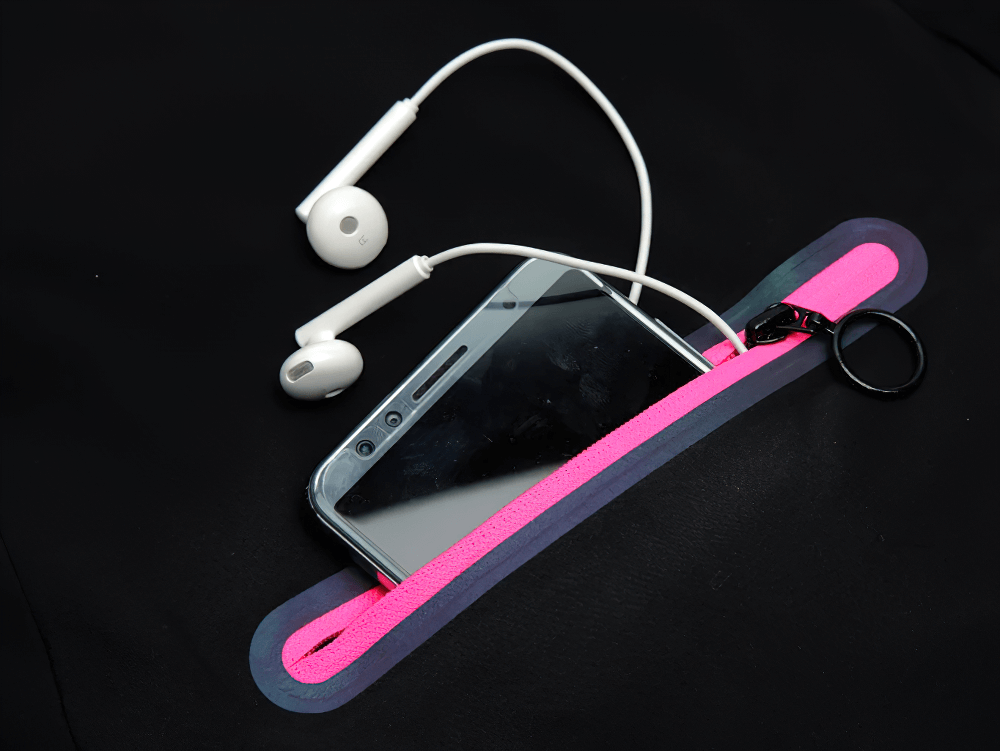 Smartphone and earphones in a pink zippered case on black background. Stylish accessory for music lovers on the go.