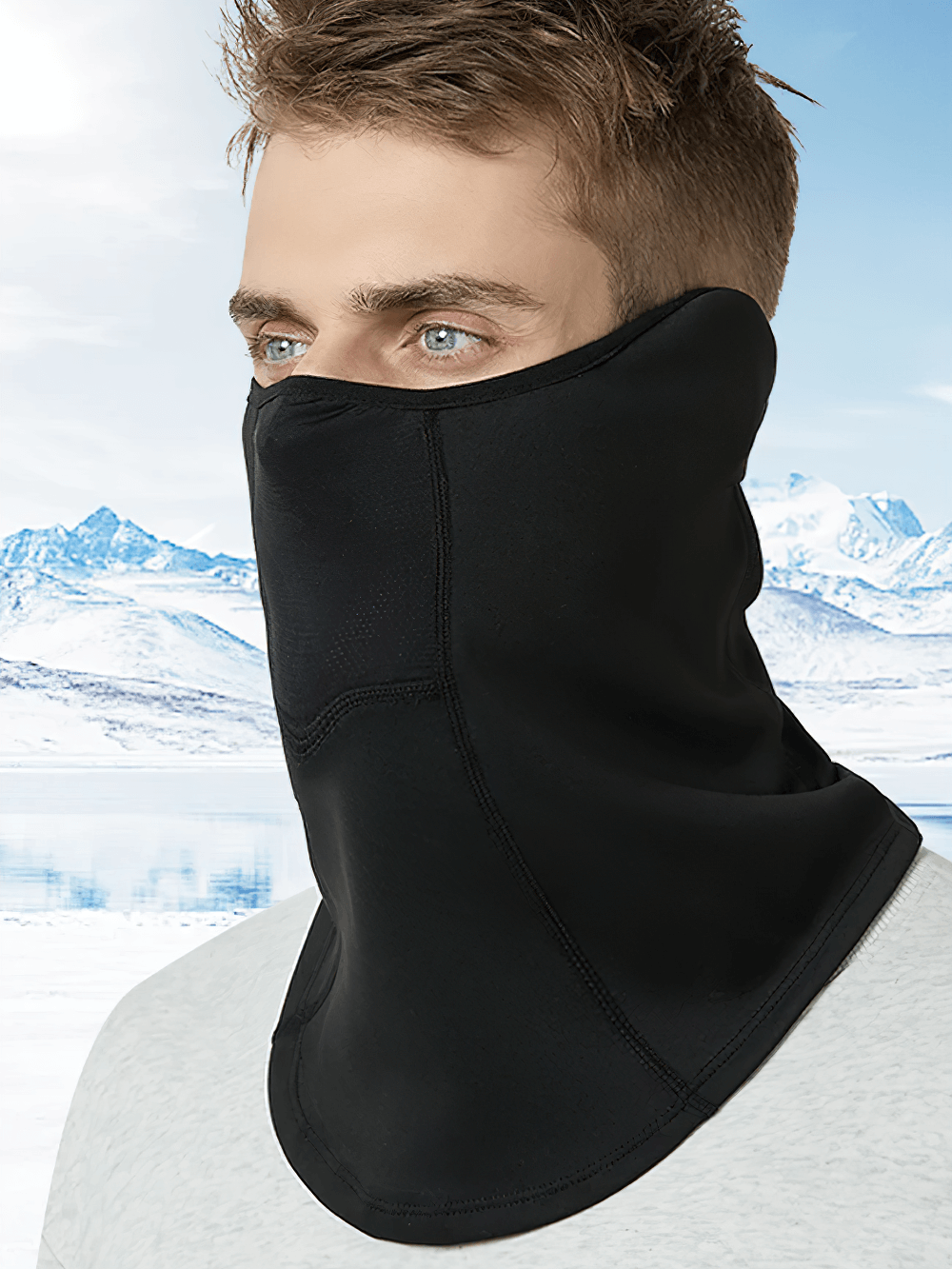 Man wearing thermal neck gaiter with extended coverage over snowy mountain backdrop, ideal for cold weather activities.