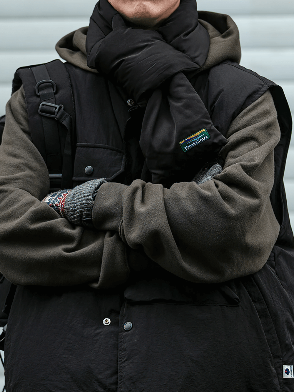 Person wearing a duck down vest with functional pockets and layered outdoor style, featuring dark tones and cozy winter accessories.