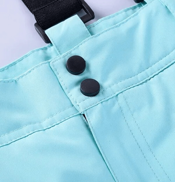 Close-up of thickened thermal skiing women's suit with buttons on turquoise pants, ideal for winter sports.