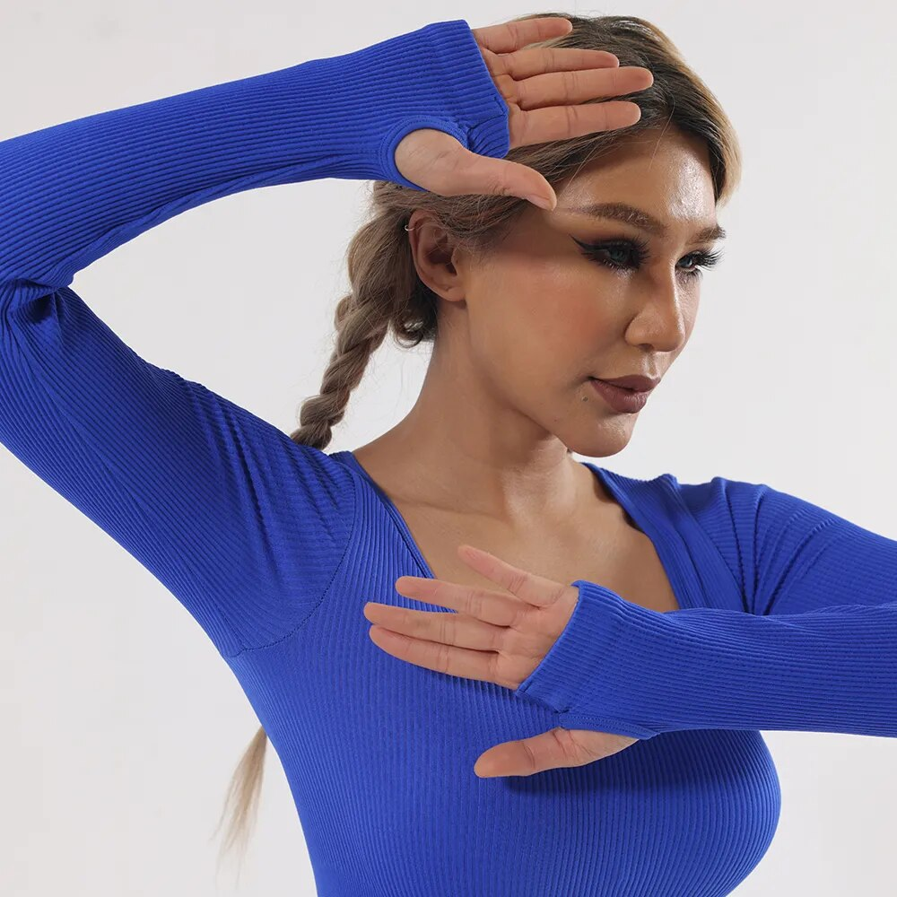 Woman posing in a tight, elastic blue one-piece sports jumpsuit, ideal for yoga and fitness, featuring long sleeves and sleek design.