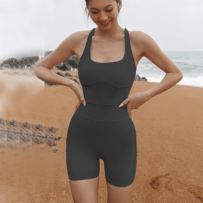 Woman wearing tight elastic one-piece workout jumpsuit for yoga on a beach
