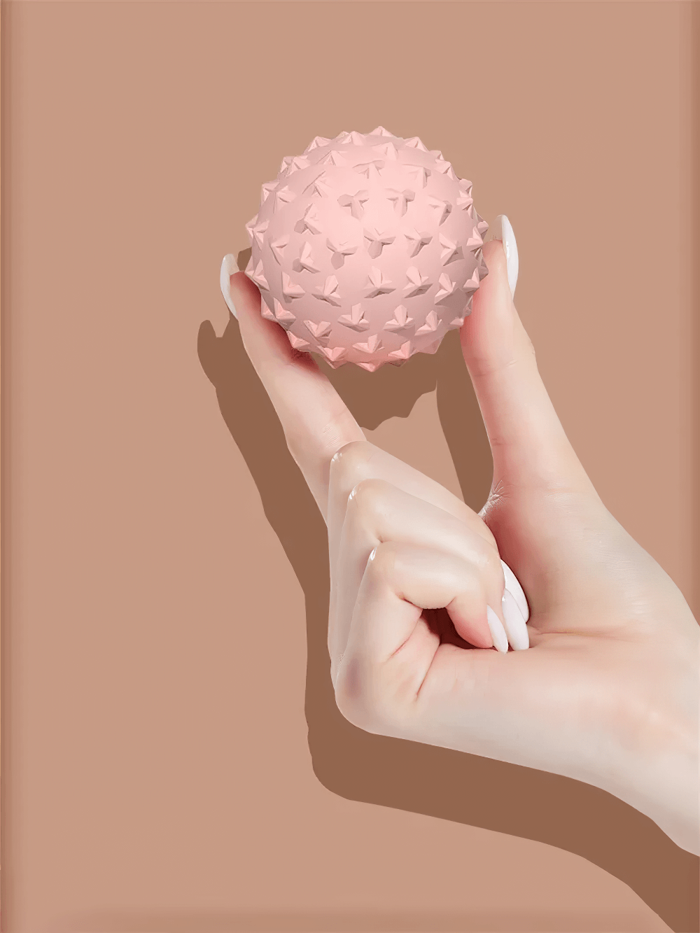 Hand holding pink TPE mini yoga massage ball for trigger points, ideal for deep muscle massage and fascia training.