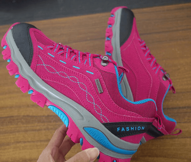 Vibrant pink trekking women's sneakers for hiking, featuring a lace-up design with supportive soles and grip-enhancing treads.