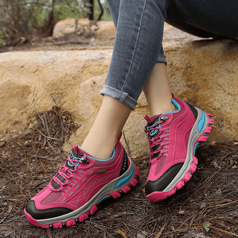 Woman wearing pink trekking women's sneakers with lace-up, ideal for hiking, showcasing comfort and durability on a trail.