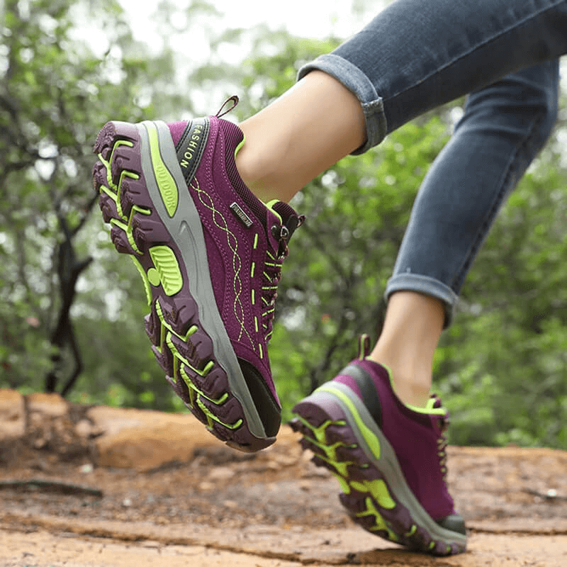 Woman hiking on trail wearing purple Trekking Women's Sneakers SF0232 with lace-up, showcasing comfort and grip for outdoor adventures.
