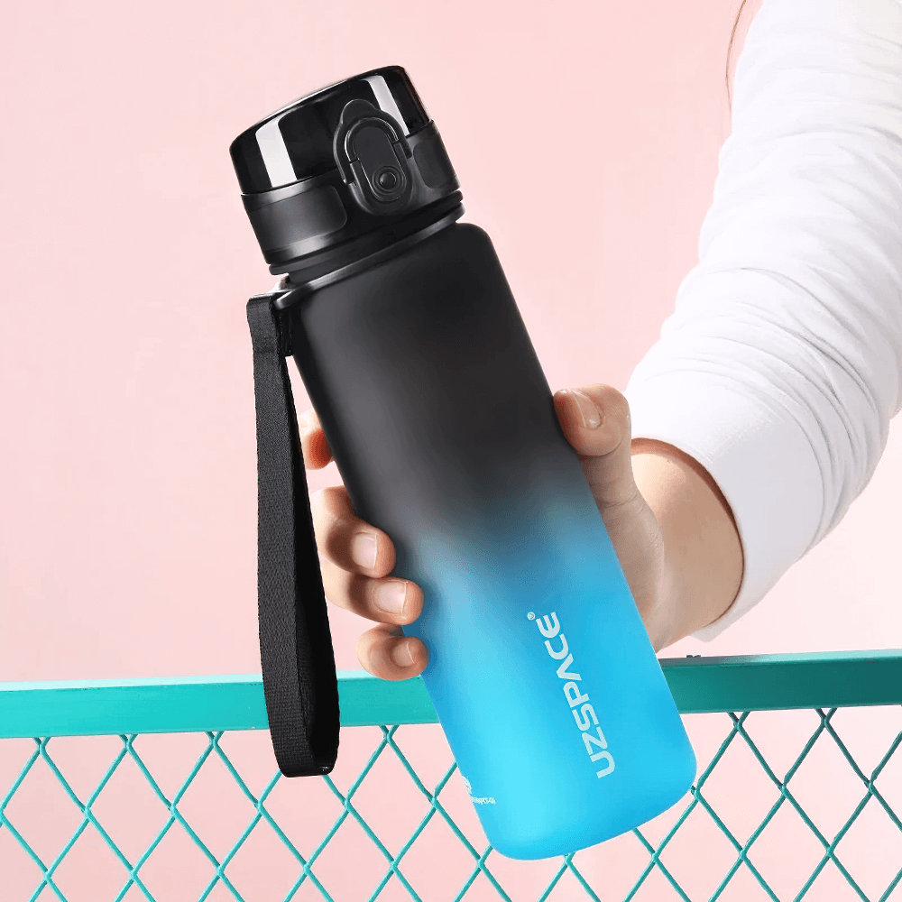 Hand holding a Tritan sports water bottle with timeline, leakproof and BPA-free design, ideal for outdoor fitness activities.