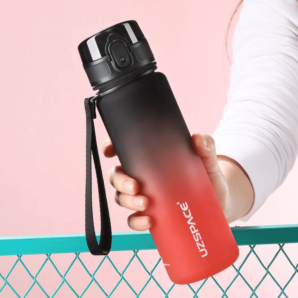 Hand holding Tritan sports water bottle with frosted finish and black cap. Perfect for outdoor fitness, leakproof design. BPA-free.