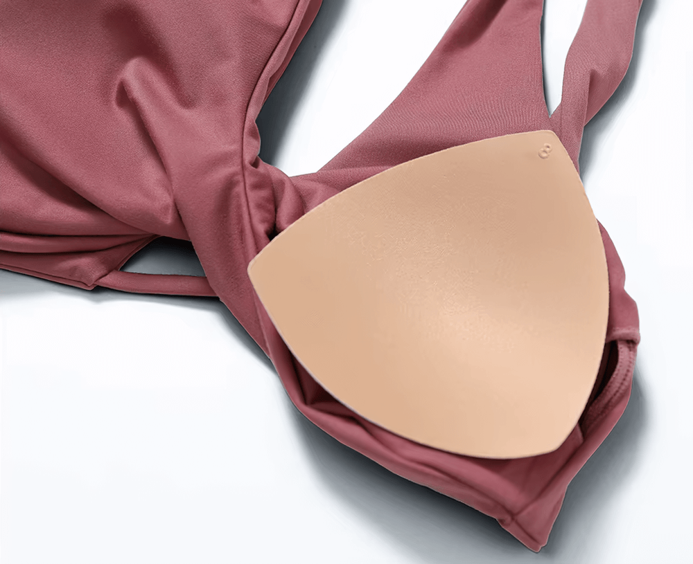 Close-up of a twist-front backless sports bra in pink with a detachable padded cup, highlighting durable nylon-spandex fabric.