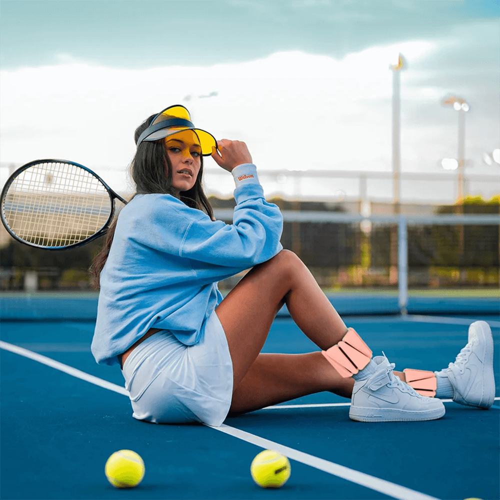 Tennis player on court wearing two-color silicone fitness bracelet weights around ankles, ready for strength training and portable fitness.