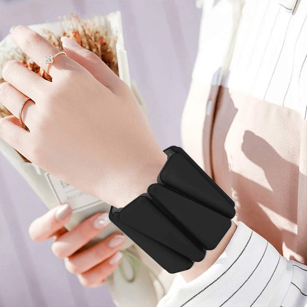 Person wearing adjustable two-color fitness bracelet weights on wrist for training and style.