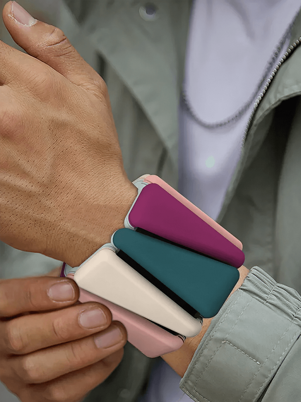 Person holding two-color fitness bracelet weights, adjustable silicone wrist and ankle bands for strength training and portable fitness.