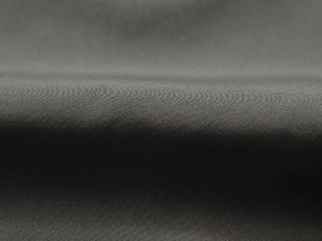 Close-up texture of black polyester fabric from men's sports tracksuit, showing sleek and smooth surface.