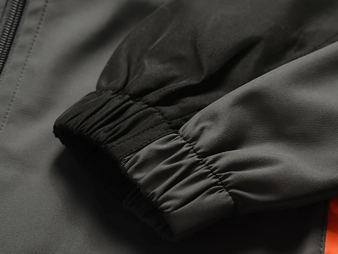 Close-up of a sleeve from a two-piece sports tracksuit jacket, featuring elastic cuffs and durable polyester fabric.