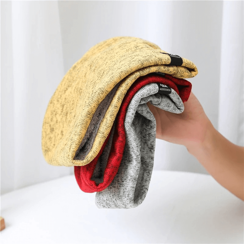 Stack of colorful fleece-lined knitted neck warmers in hand, showcasing yellow, red, and gray options for cozy winter fashion.