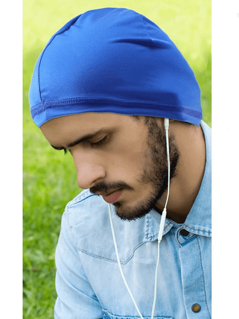 Man wearing blue Unisex Lightweight Quick-Dry Sports Skull Cap SF2240 while listening to music outdoors, showcasing sun protection.