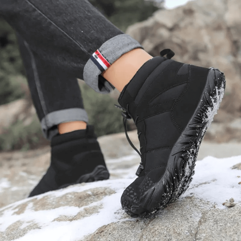 Person wearing unisex waterproof hiking boots SF1920, stepping confidently on a snowy mountain for superior outdoor adventures.
