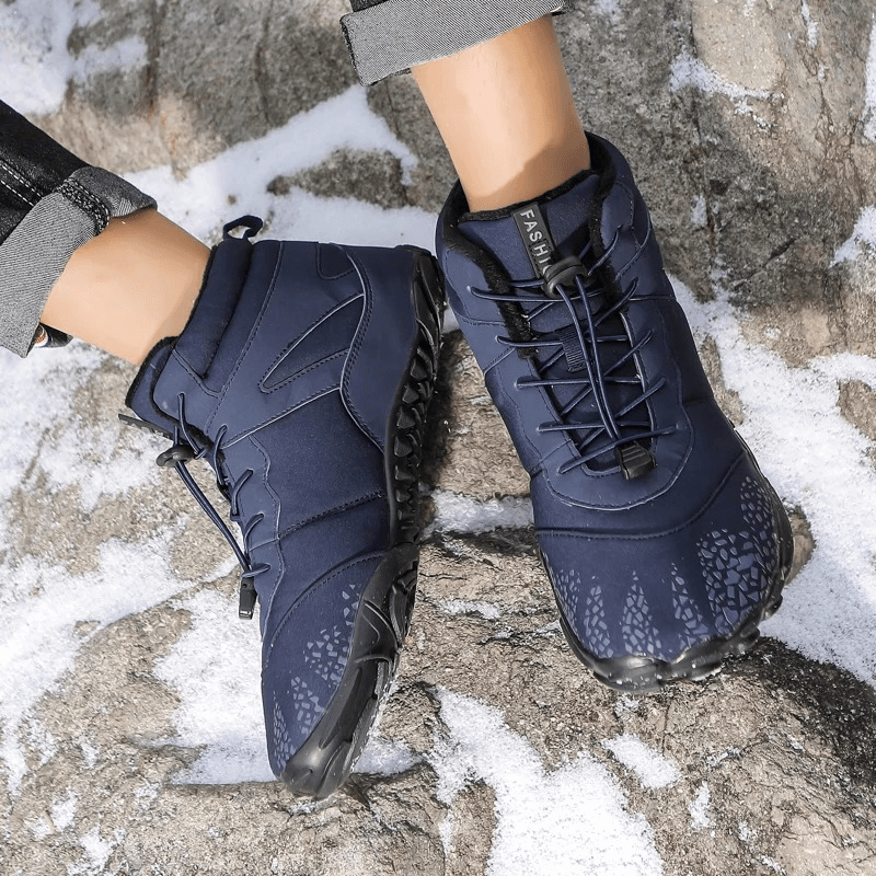 Unisex waterproof hiking boots with non-slip soles on snowy rocks, showcasing durability and style for outdoor activities.