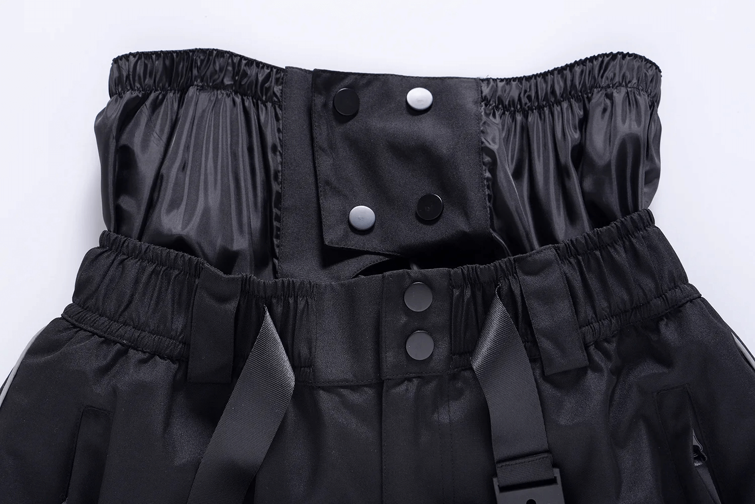 Close-up of black waterproof ski pants with adjustable waistband and button detail for winter sports.