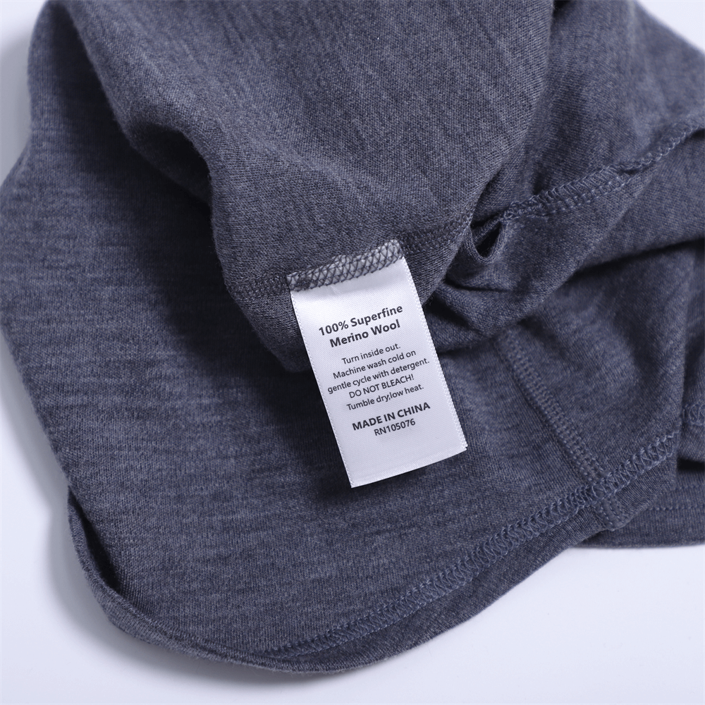 Close-up of unisex windproof wool balaclava fabric tag displaying 100% superfine merino wool, perfect for skiing and outdoor comfort.