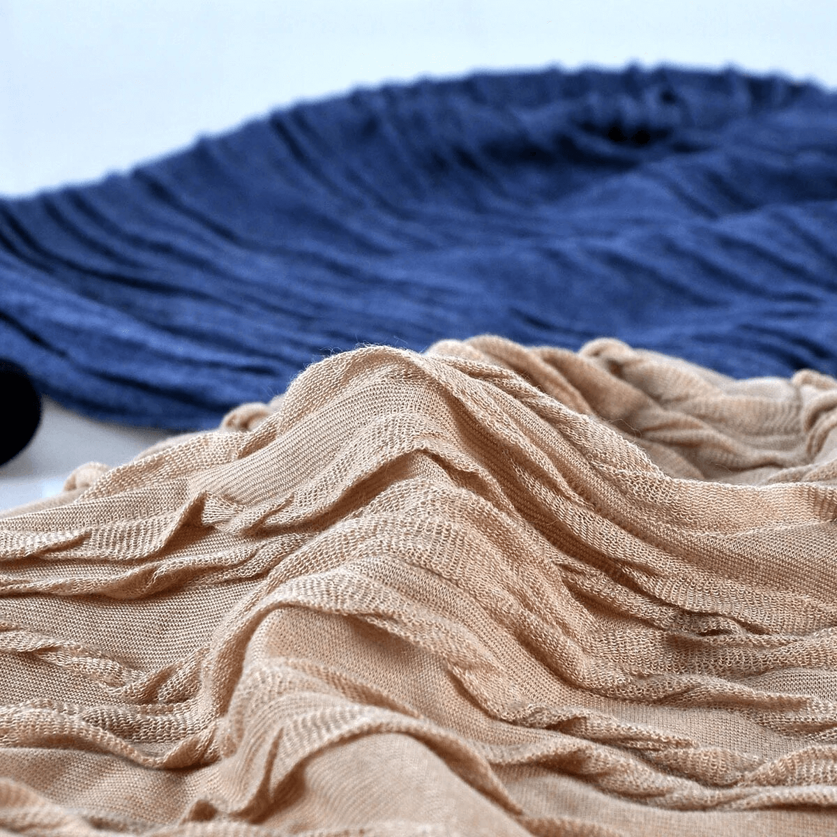 Close-up of unisex baggy solid beanies in tan and navy, highlighting the warm, windproof texture and cotton material.