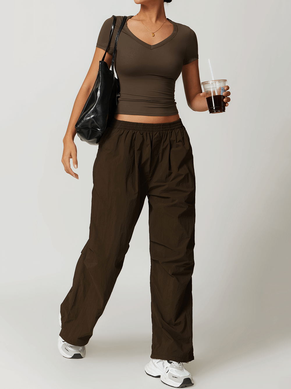 Woman in stylish v-neck yoga tee and pants, holding a drink. Perfect for yoga, running, featuring breathable and quick-drying fabric.