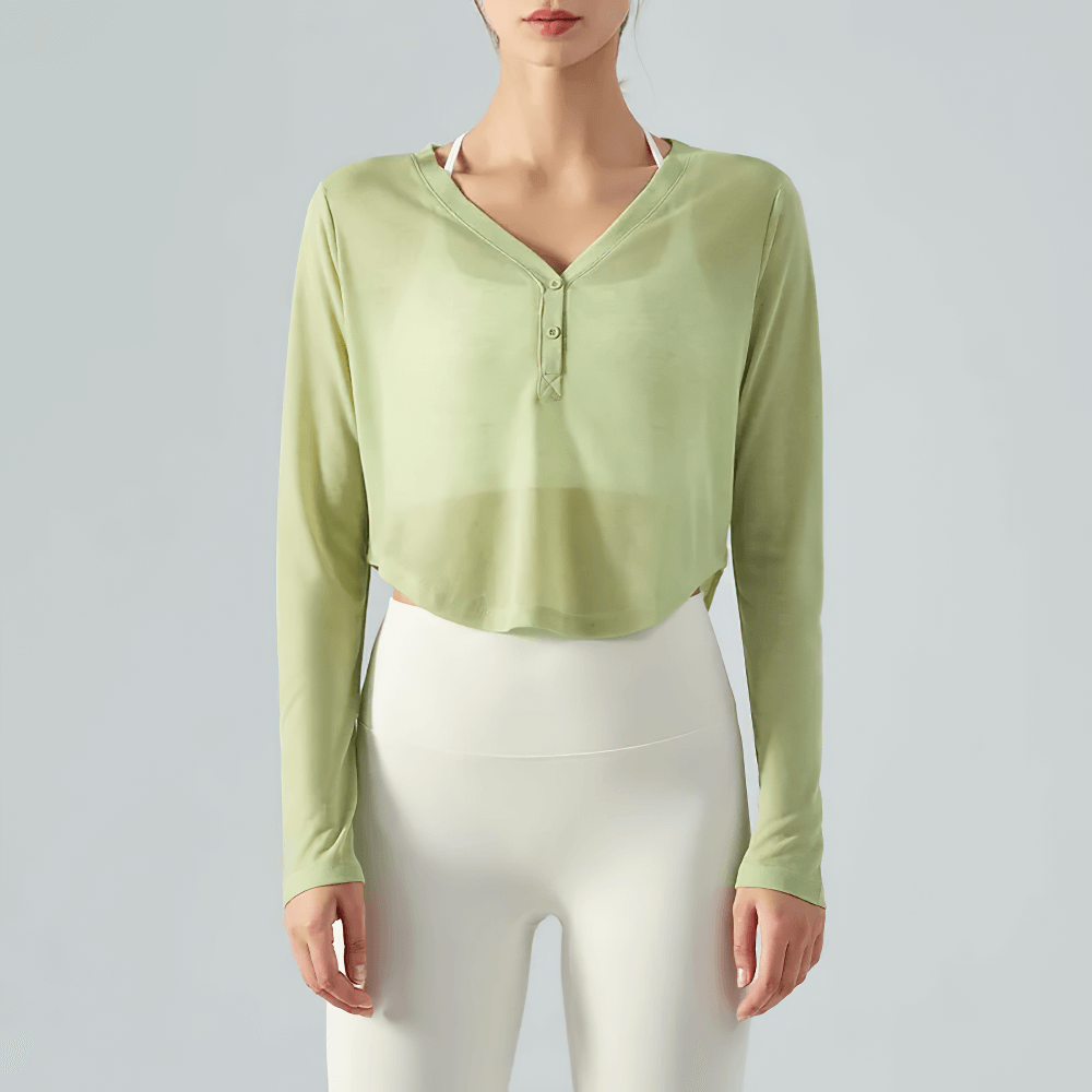 Woman wearing a green V-neck yoga top with long sleeves and curved hem. Breathable, lightweight fitness apparel for women.