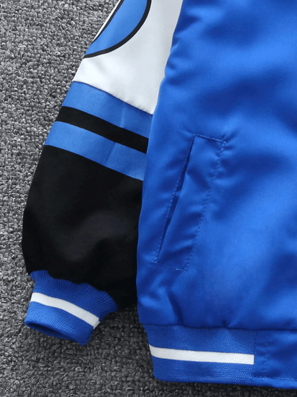 Close-up of kids' varsity bomber jacket SF3114 with bold lettering and vibrant color mix. Perfect for sporty youth fashion.