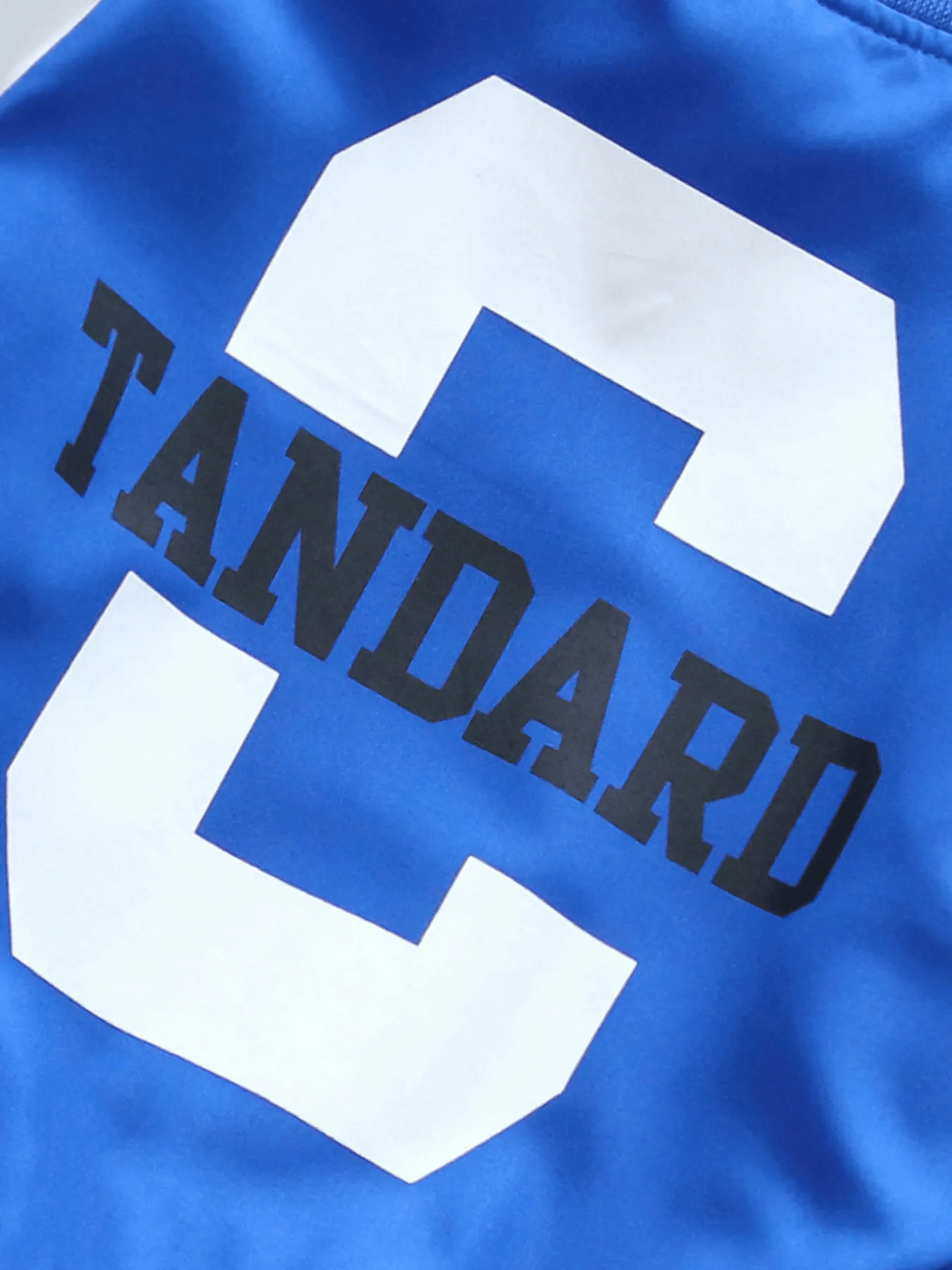 Close-up of blue varsity bomber jacket with bold white 'C' and black 'Tandard' lettering, ideal for sporty kids' fashion.