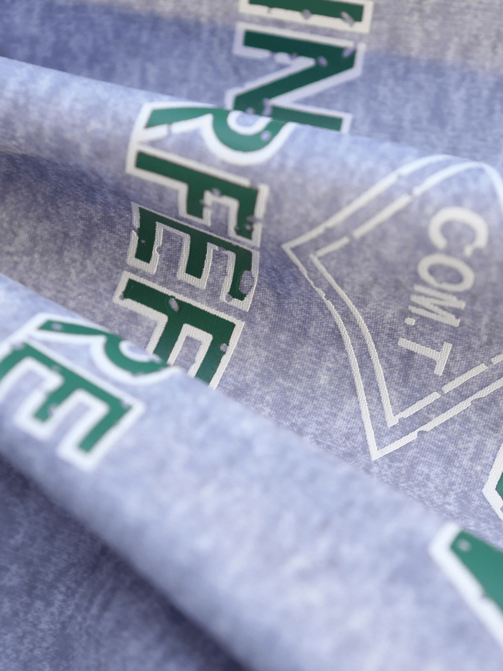 Close-up view of a gray sweatshirt with green lettering and graphic print.