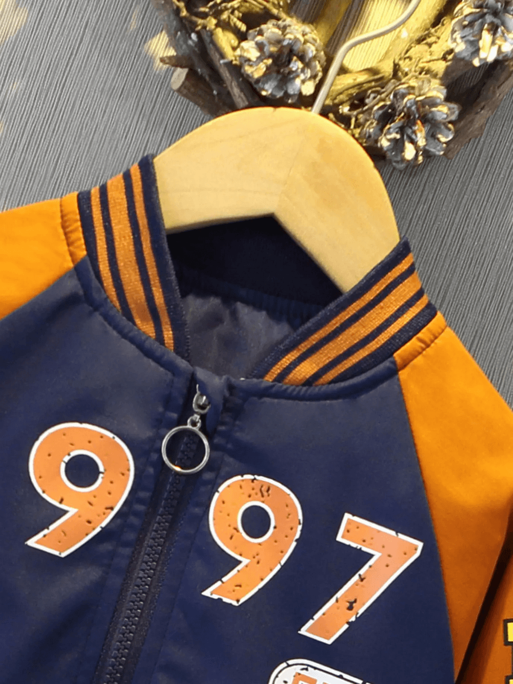 Kids varsity jacket with basketball print, featuring orange and navy colors, zip closure, and sporty design. Perfect for young sports fans.