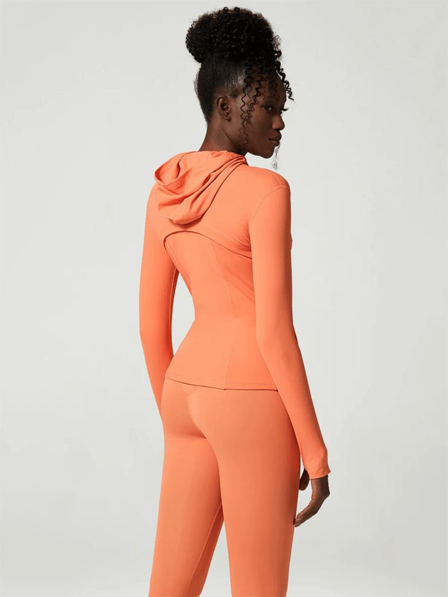 Woman wearing orange versatile yoga and gym activewear set showing back view, featuring full-sleeve top and leggings, perfect for fitness.