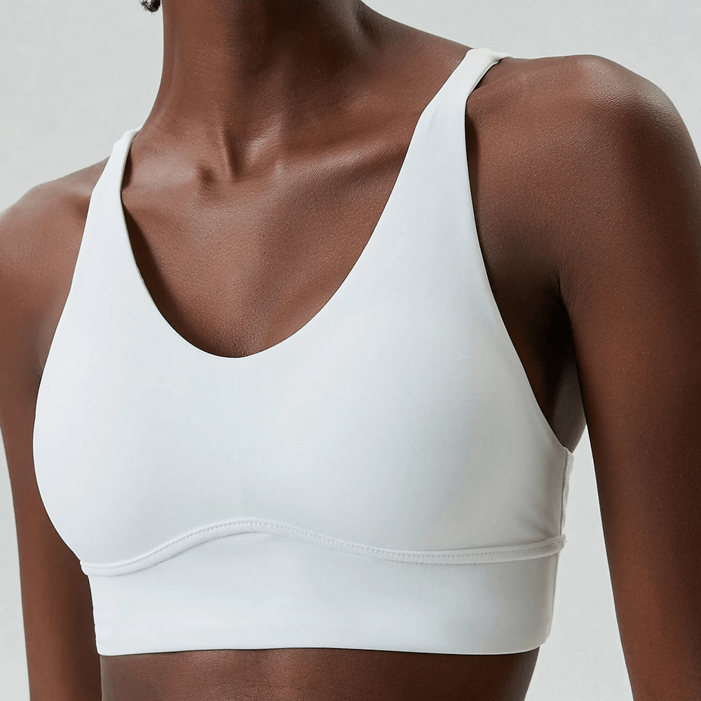 Model wearing a sleek white sports bra with a minimalist design, perfect for workouts and gym sessions.