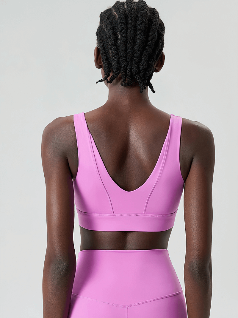 Woman wearing vibrant pink yoga fitness bra, back view showing breathable, anti-friction fabric design for optimal movement.