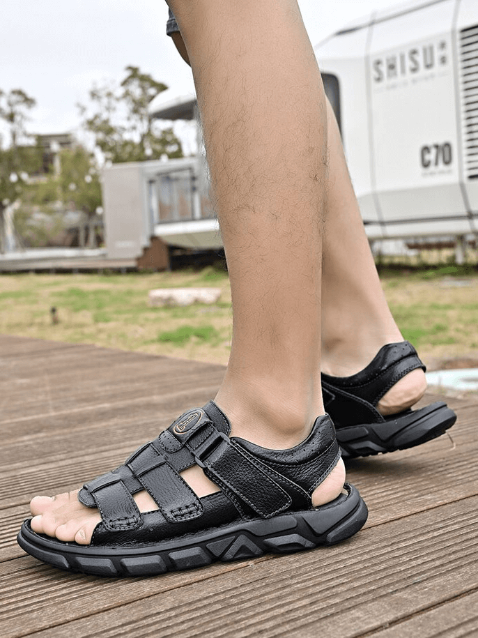 Man wearing vintage soft bottom trekking sandals on wooden deck, showcasing comfort and style for outdoor adventures.