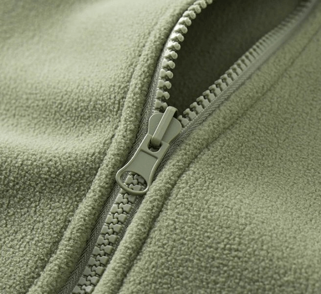 Close-up of green sports fleece jacket zipper showing texture and durability, perfect for cold weather activities, unisex design.